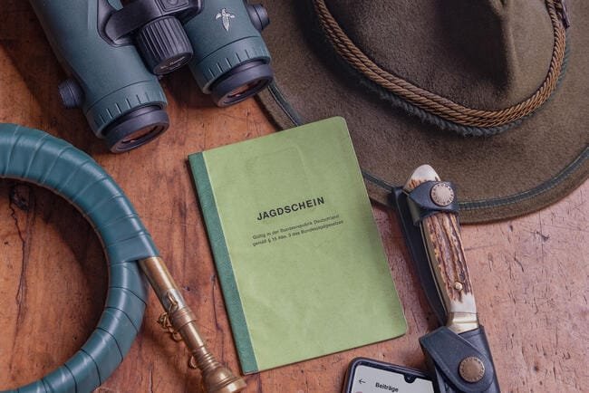 Jagdschein wird zum Kauf angeboten-Jagdschein auf einem Tisch mit einem Fernglas